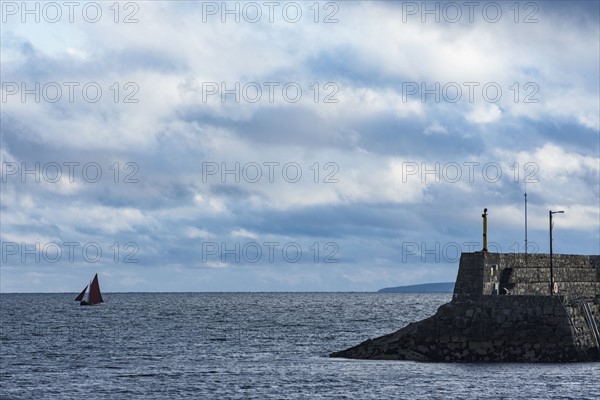 Ireland, Galway County, Spiddal, Hooker sailboat and pier