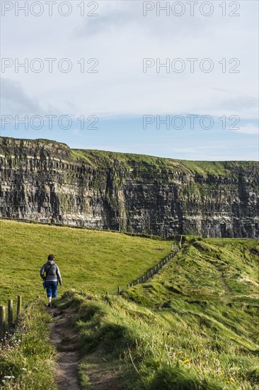 Ireland, Clare County, Woman walking along Cliffs of Moher