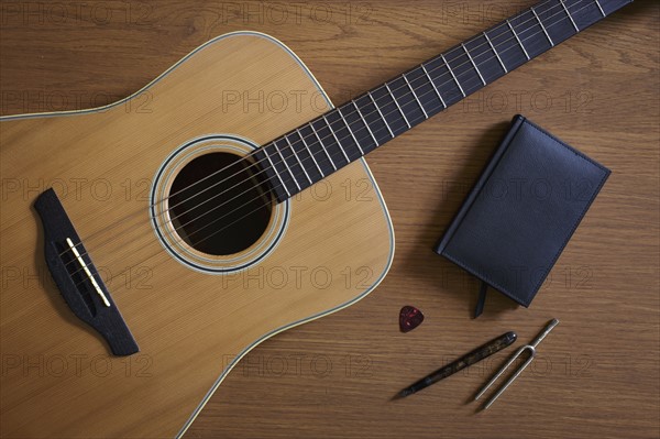 Acoustic guitar and tuning fork lying on floor