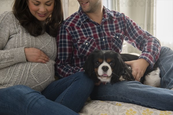 Mid adult couple sitting on sofa with puppy