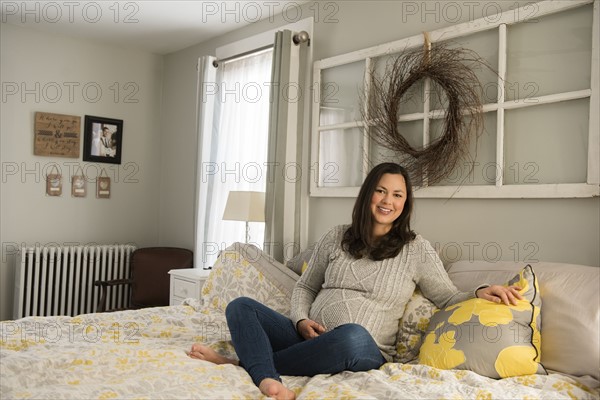 Pregnant woman sitting on bed