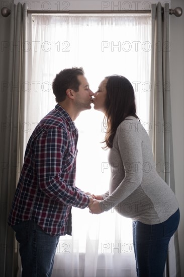Mid adult couple kissing in front of window