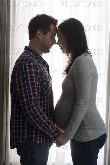 Mid adult couple in front of window, face to face