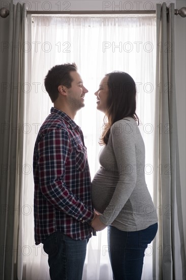 Mid adult couple in front of window, laughing