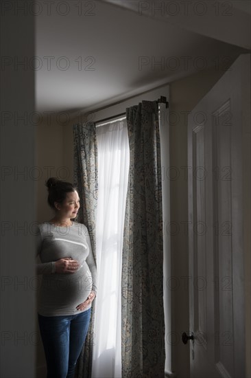 Pregnant woman looking through window