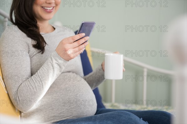 Pregnant woman sitting and using smart phone