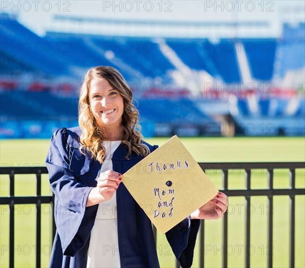 Portrait of graduate student showing message on mortarboard