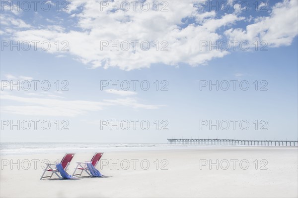 Deck chairs on sandy beach by Atlantic Ocean