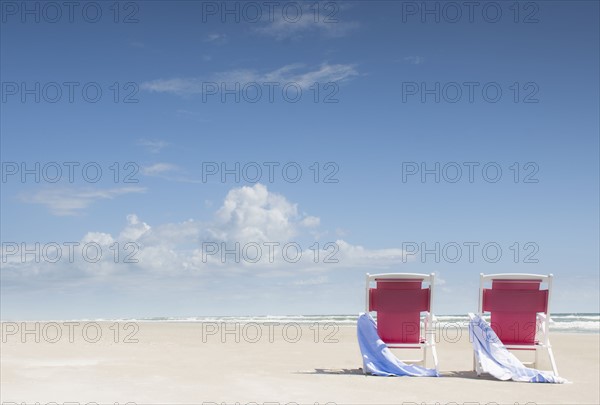 Deck chairs with towels on sandy beach by Atlantic Ocean