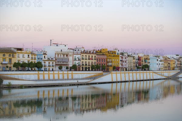Spain, Seville, Colorful residential building reflecting in Guadalquivir river