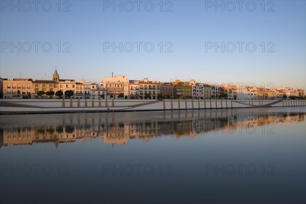 Spain, Seville, Colorful residential building reflecting in Guadalquivir river