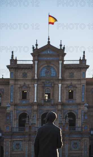 Spain, Andalusia, Seville, Facade with spanish flag and statue of Anibal Gonzales in Plaza de Espana