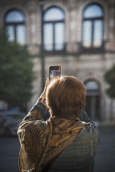 Spain, Andalusia, Seville, Plaza Nueva, Woman taking photo of building with smartphone