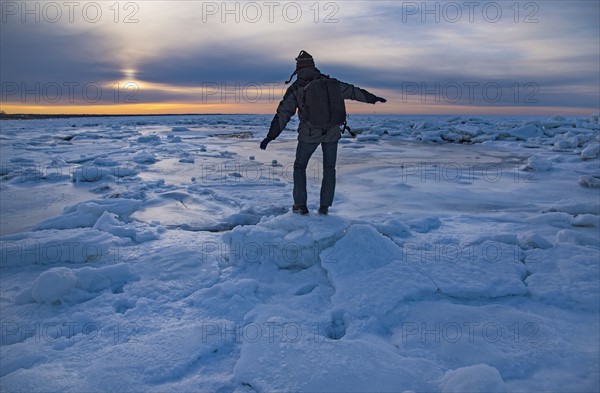 USA, Massachusetts, Cape Cod, Eastham, Man balancing on sea ice at dusk