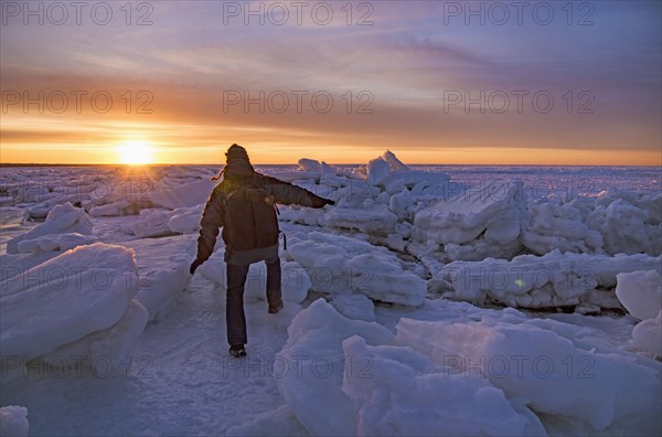 USA, Massachusetts, Cape Cod, Eastham, Man balancing on sea ice at dusk