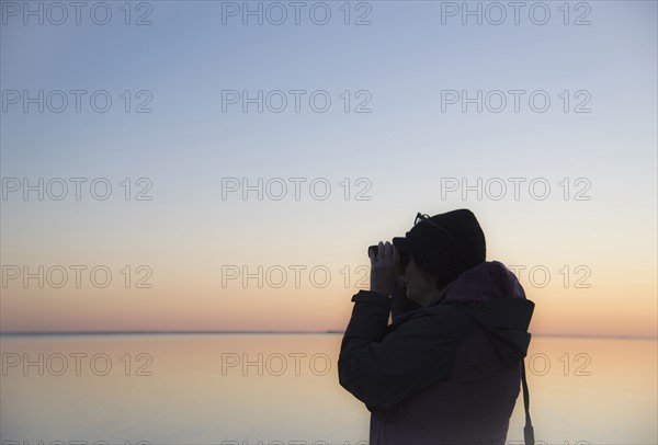 Senior woman birdwatching at sunset