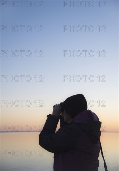 Senior woman birdwatching at sunset