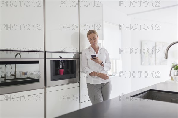 Woman using phone in kitchen