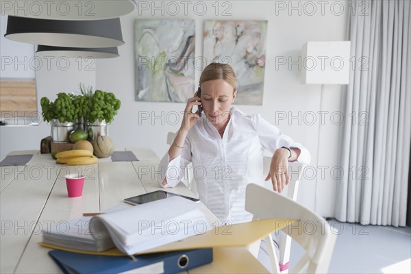 Woman working and talking on phone in dining room