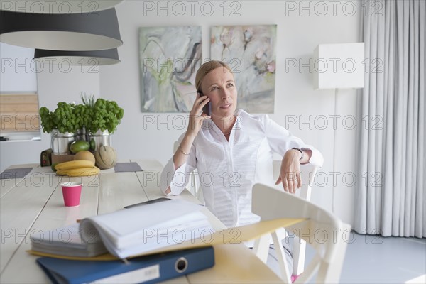 Woman working and talking on phone in dining room