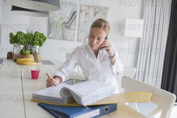 Woman working and talking on phone in dining room