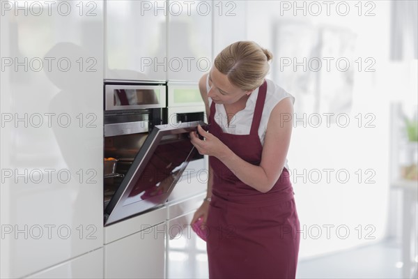 Woman using oven in kitchen