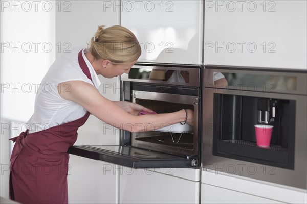 Woman using oven in kitchen