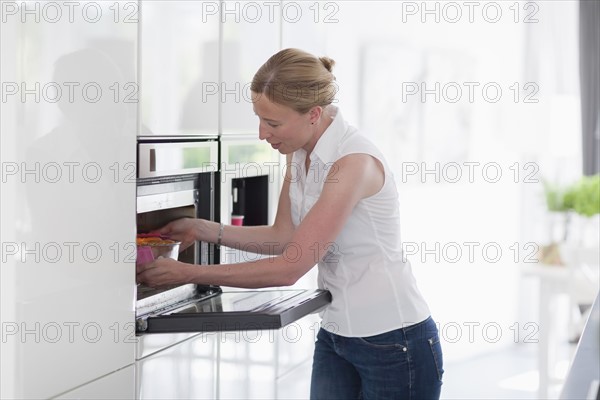 Woman using oven in kitchen