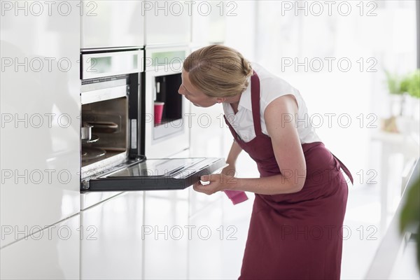 Woman using oven in kitchen