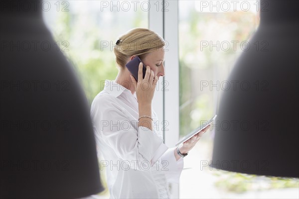 Woman talking on phone and using digital tablet