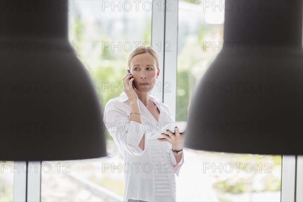 Woman talking on phone and using digital tablet