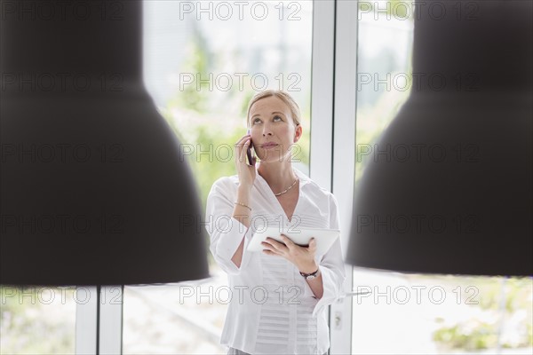 Woman talking on phone and using digital tablet