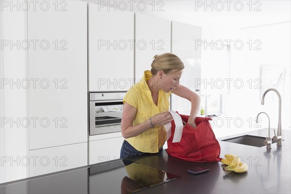 Mature woman unpacking groceries in modern kitchen