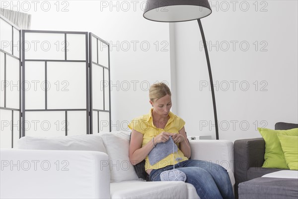 Mature woman knitting in modern living room