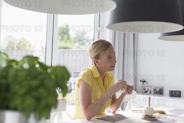 Mature woman making macrame at table