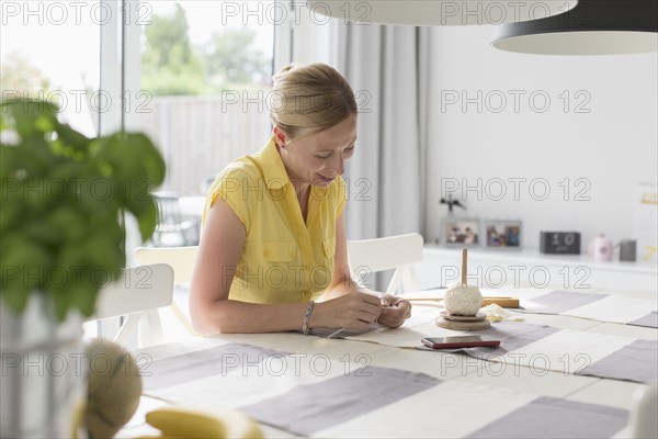 Mature woman making macrame at table