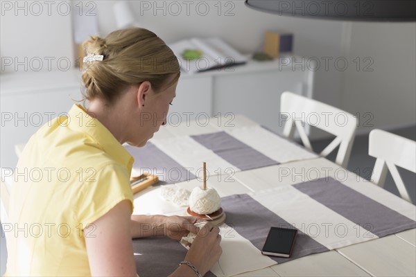 Mature woman making macrame at table