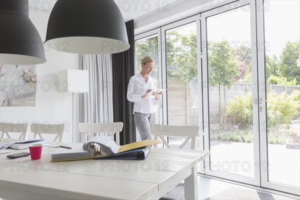 Mature woman working with mobile devices in modern living room