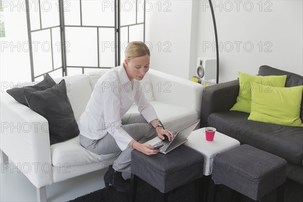 Mature woman sitting in modern living room and using laptop