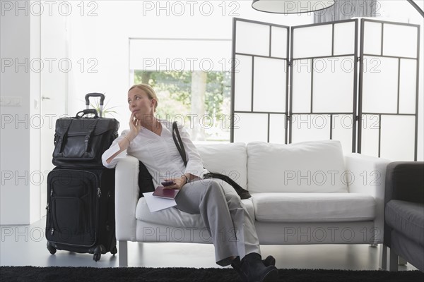 Mature woman waiting with luggage in modern living room