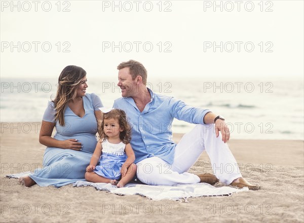 Family sitting on blanket on beach