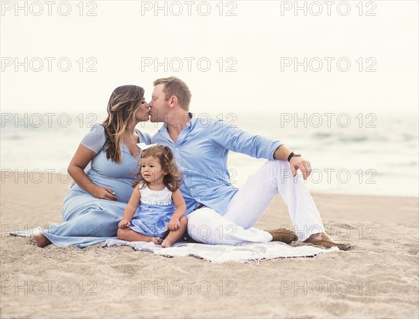 Family sitting on blanket on beach