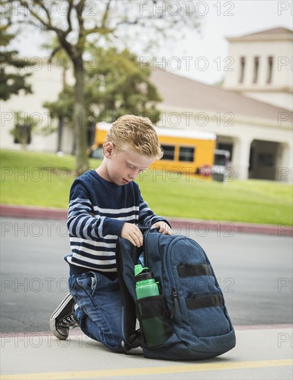 Boy kneeling by backpack