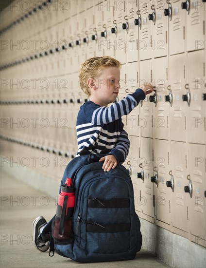 Boy with backpack by school lockers