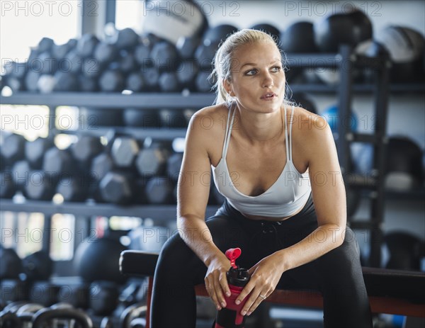 Young woman holding bottle in gym