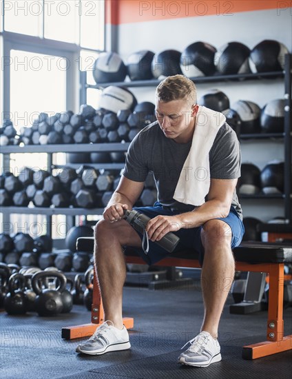 Mid adult man with towel and bottle in gym