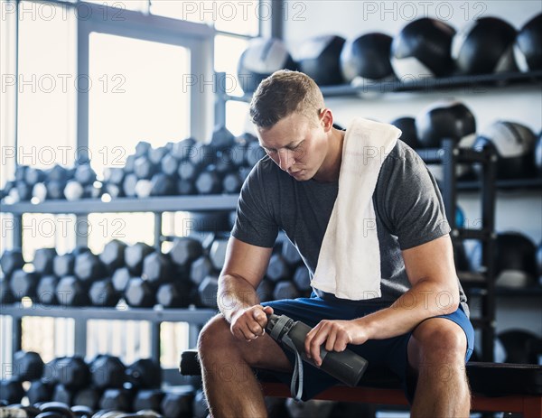 Mid adult man with towel and bottle in gym