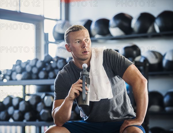 Mid adult man with towel and bottle in gym