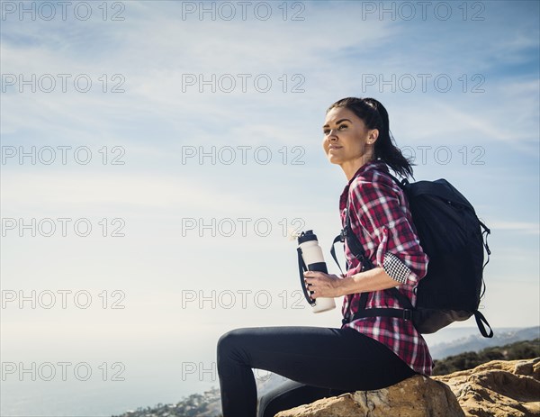 Woman with water bottle sitting on rock