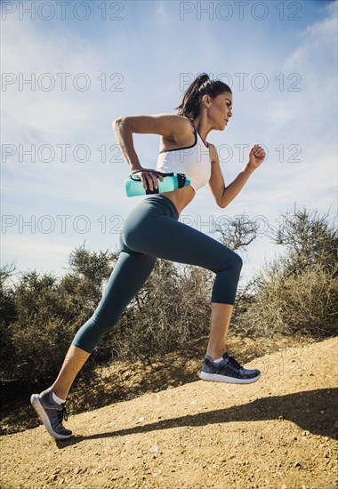 Woman jogging on mountain with water bottle